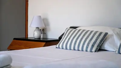 a bed with a pillow and a lamp on a table at Irene Double Apartment Anoi in Symi