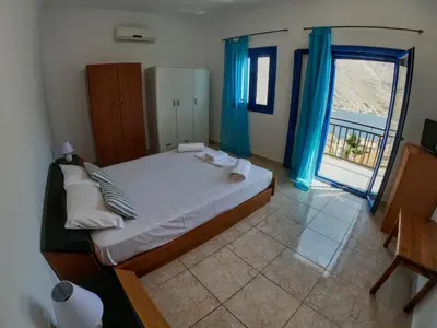 a bedroom with a bed with blue curtains and a window at Irene Double Apartment Anoi in Symi