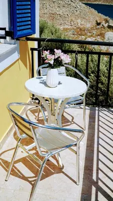 a white table with two chairs and a vase of flowers at Irene Double Apartment Anoi in Symi