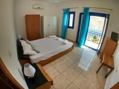 a bedroom with a large bed with blue curtains at Irene Double Apartment Anoi in Symi