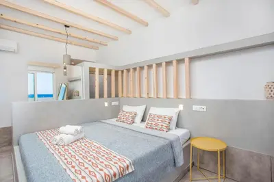 a bedroom with two beds and a yellow stool at Alexander Studios & Suites - Adults Only in Faliraki