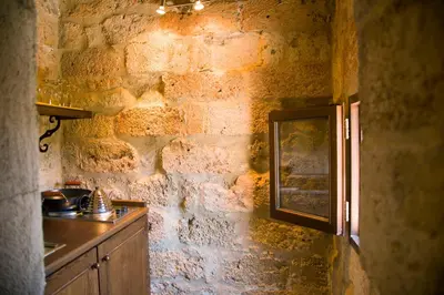 a kitchen with a stone wall with a sink and a window at Mystic Hotel - Adults only in Rhodes Town