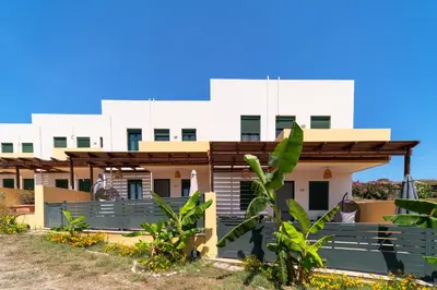 a building on the beach with plants in the foreground at Mare Blu 1 on the beach in Gennadi