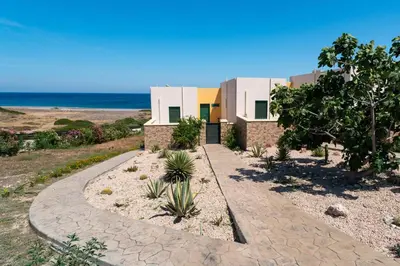 a house on the beach with a walkway at Mare Blu 1 on the beach in Gennadi