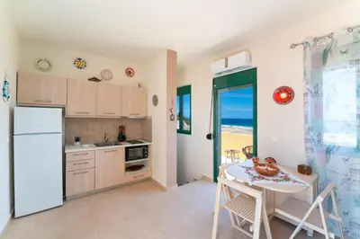 a kitchen with a table and a white refrigerator at Mare Blu 2 on the beach in Gennadi
