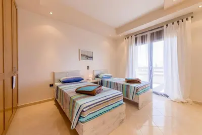 two beds in a room with a large window at Lucia's Secret Garden in Asgourou