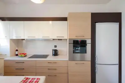 a kitchen with white cabinets and a refrigerator at Holiday Nest & parking in Ialyssos