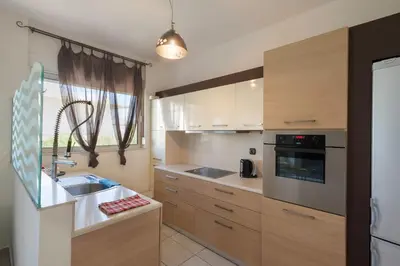 a kitchen with wooden cabinets and a sink at Holiday Nest & parking in Ialyssos