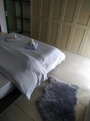 a bed with white sheets and a furry rug on the floor at Holiday Nest & parking in Ialyssos