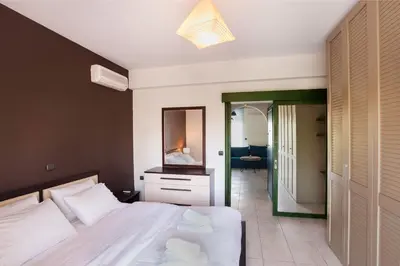 a bedroom with a large white bed and a mirror at Holiday Nest & parking in Ialyssos