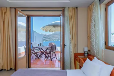a bedroom with a bed and a balcony with a table at Stefanakis Villas - Car Included in Livadia