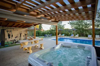 a hot tub under a pergola next to a pool at Sun's Reach Villa in Rhodes Town