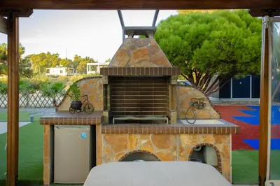 a outdoor grill with a pizza oven in a yard at Sun's Reach Villa in Rhodes Town