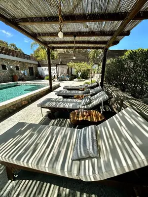 a row of chaise lounges on a patio next to a pool at Aithonas Villa in Archangelos