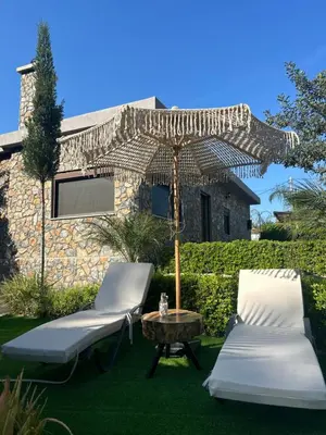 a patio with two chairs and an umbrella and a table at Aithonas Villa in Archangelos