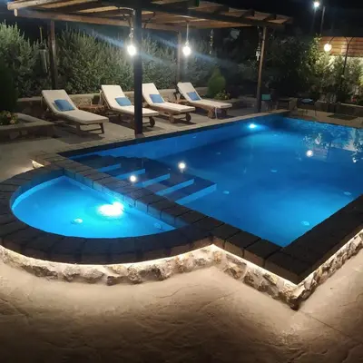a swimming pool in a backyard at night at Aithonas Villa in Archangelos
