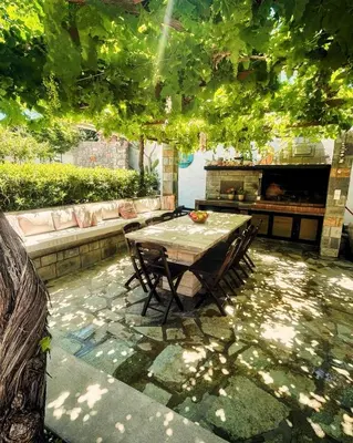 a table and chairs on a patio under a tree at Aithonas Villa in Archangelos