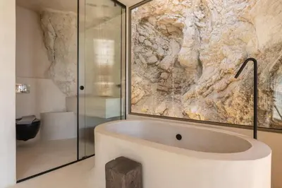 a bath tub in a bathroom with a stone wall at Stone Luxury Suites - Adults Only in Archangelos