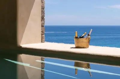 a basket of wine bottles sitting on a ledge overlooking the ocean at Stone Luxury Suites - Adults Only in Archangelos
