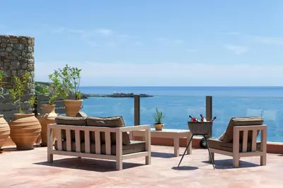 a patio with two benches and a table and chairs at Stone Luxury Suites - Adults Only in Archangelos