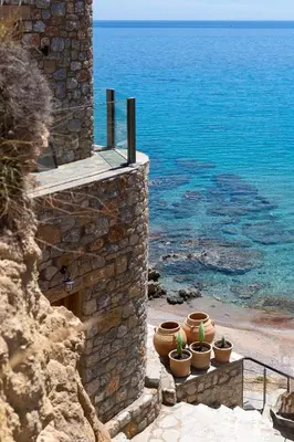a group of pots sitting on a wall next to the ocean at Stone Luxury Suites - Adults Only in Archangelos