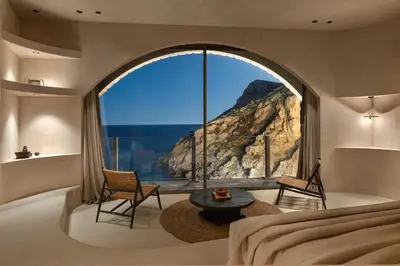 a bedroom with a large window with a mountain view at Stone Luxury Suites - Adults Only in Archangelos
