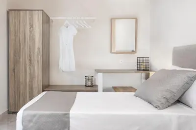 a white bedroom with a white bed and a dresser at ANASTASIOS HOUSE STEGNA in Archangelos