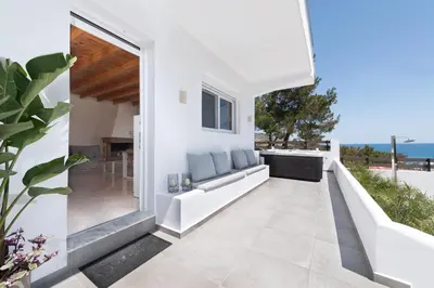a white house with a balcony with a view of the ocean at ANASTASIOS HOUSE STEGNA in Archangelos
