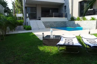 a backyard with two lawn chairs and a swimming pool at Ixia Breeze 1 in Ixia