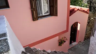 a pink house with stairs and a window at Armonia House in Symi