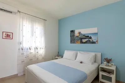 a bedroom with a white bed and a blue wall at House Myrtos in Lachania