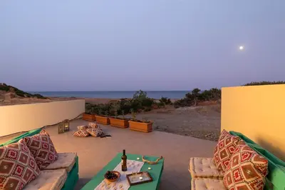 a patio with couches and a table and the ocean at House Myrtos in Lachania