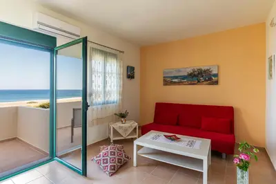 a living room with a red couch and a view of the ocean at House Myrtos in Lachania