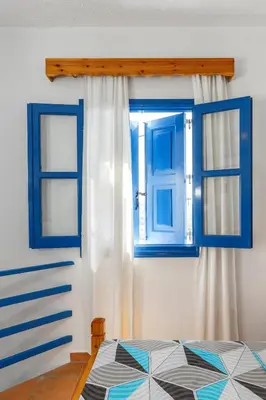 a bedroom with two blue windows and a bed at House Salvia in Lachania