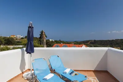 two blue chairs and an umbrella on a balcony at House Salvia in Lachania