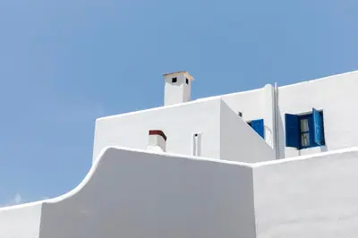 a white building with blue windows and a blue sky at House Salvia in Lachania
