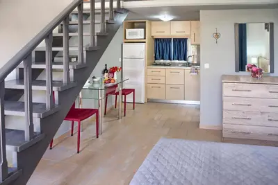 a kitchen with a staircase and a table with red chairs at Haraki Sand Beach in Haraki