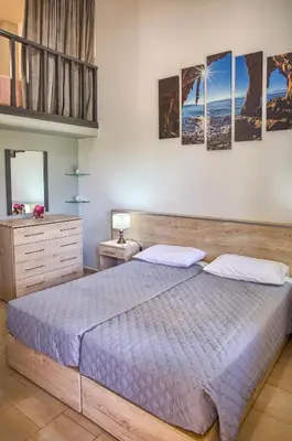 a bedroom with a large bed and some pictures on the wall at Haraki Sand Beach in Haraki