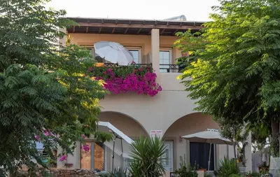a building with a balcony with an umbrella and flowers at Haraki Sand Beach in Haraki