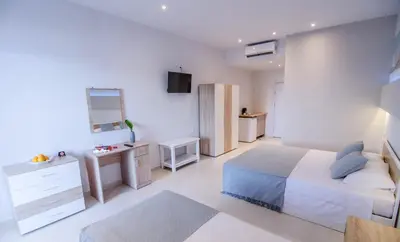 a white bedroom with a bed and a desk at Galazio Beach in Faliraki