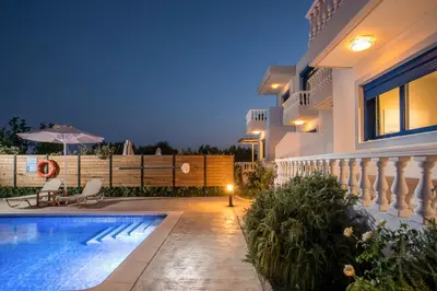 a house with a swimming pool at night at RITA MARE seafront villas heated Pools in Gennadi