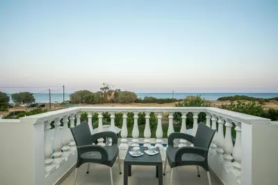 a balcony with chairs and a table and the ocean at RITA MARE seafront villas heated Pools in Gennadi