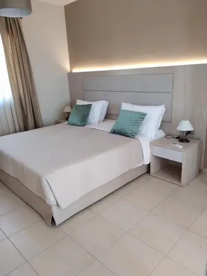 a bedroom with a large white bed with green pillows at RITA MARE seafront villas heated Pools in Gennadi