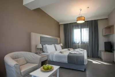 a hotel room with a bed and a chair at RITA MARE seafront villas heated Pools in Gennadi