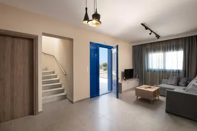 a living room with a blue door and a couch at RITA MARE seafront villas heated Pools in Gennadi