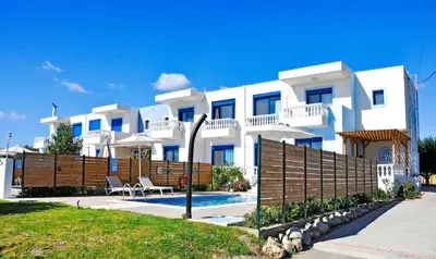 a large white building with a fence in front of it at RITA MARE seafront villas heated Pools in Gennadi