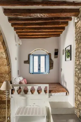 a bedroom in a house with white walls and wooden ceilings at Casa Blue in Gennadi