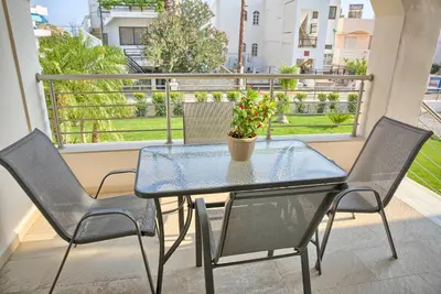 a glass table with two chairs and a potted plant on a balcony at Haraki Bay Hotel and Luxury Apartments in Haraki