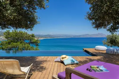 a wooden deck with a view of a body of water at lindos kerylos villa in Líndos