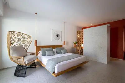 a bedroom with a bed and a chair at Kouros Exclusive Hotel & Suites - Adults Only in Faliraki